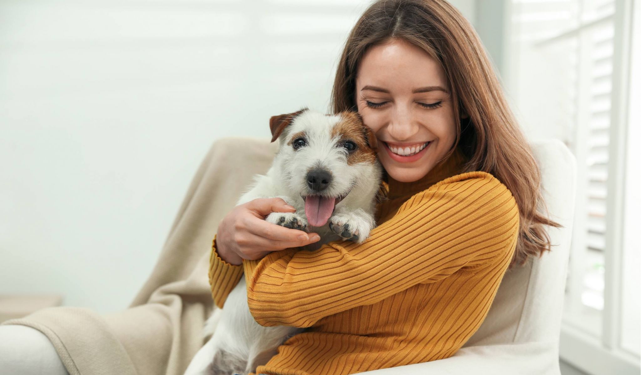 Young woman cuddling with her cute Jack Russell Terrier at home