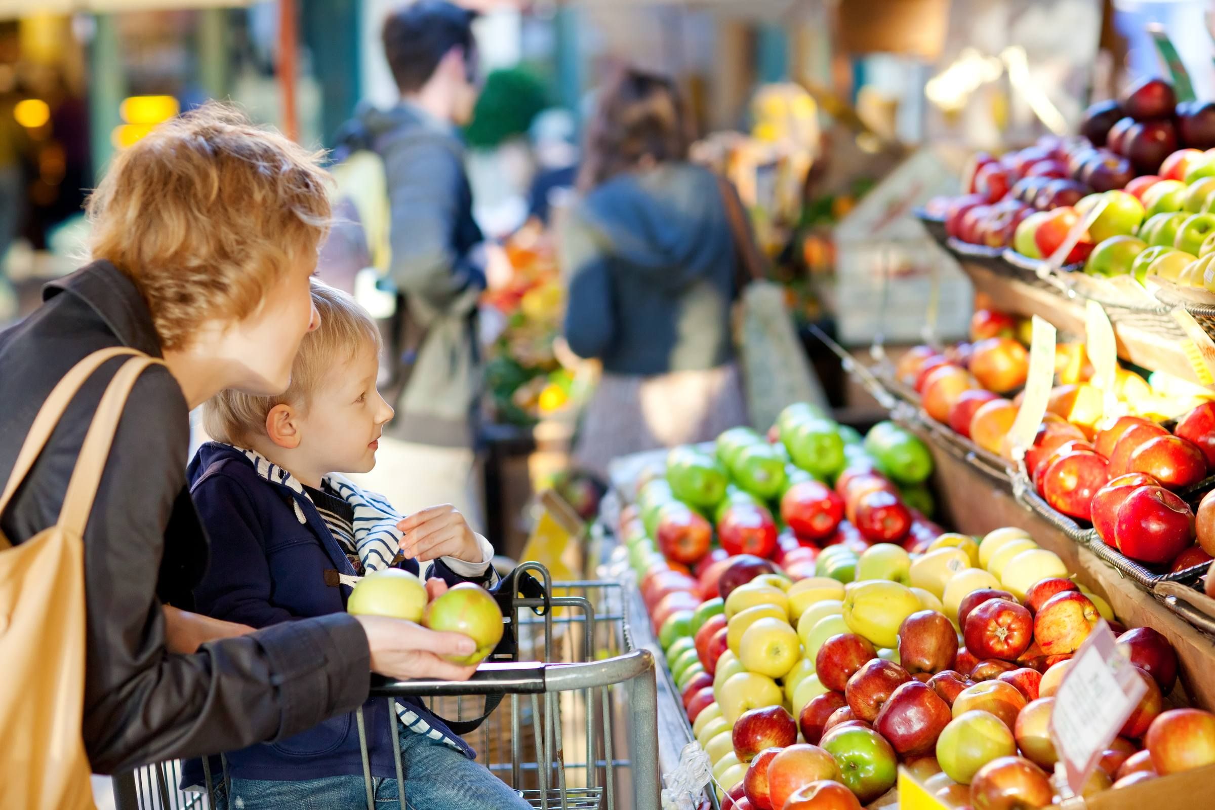 Mother and her toddler son buying fruits at a farmers market