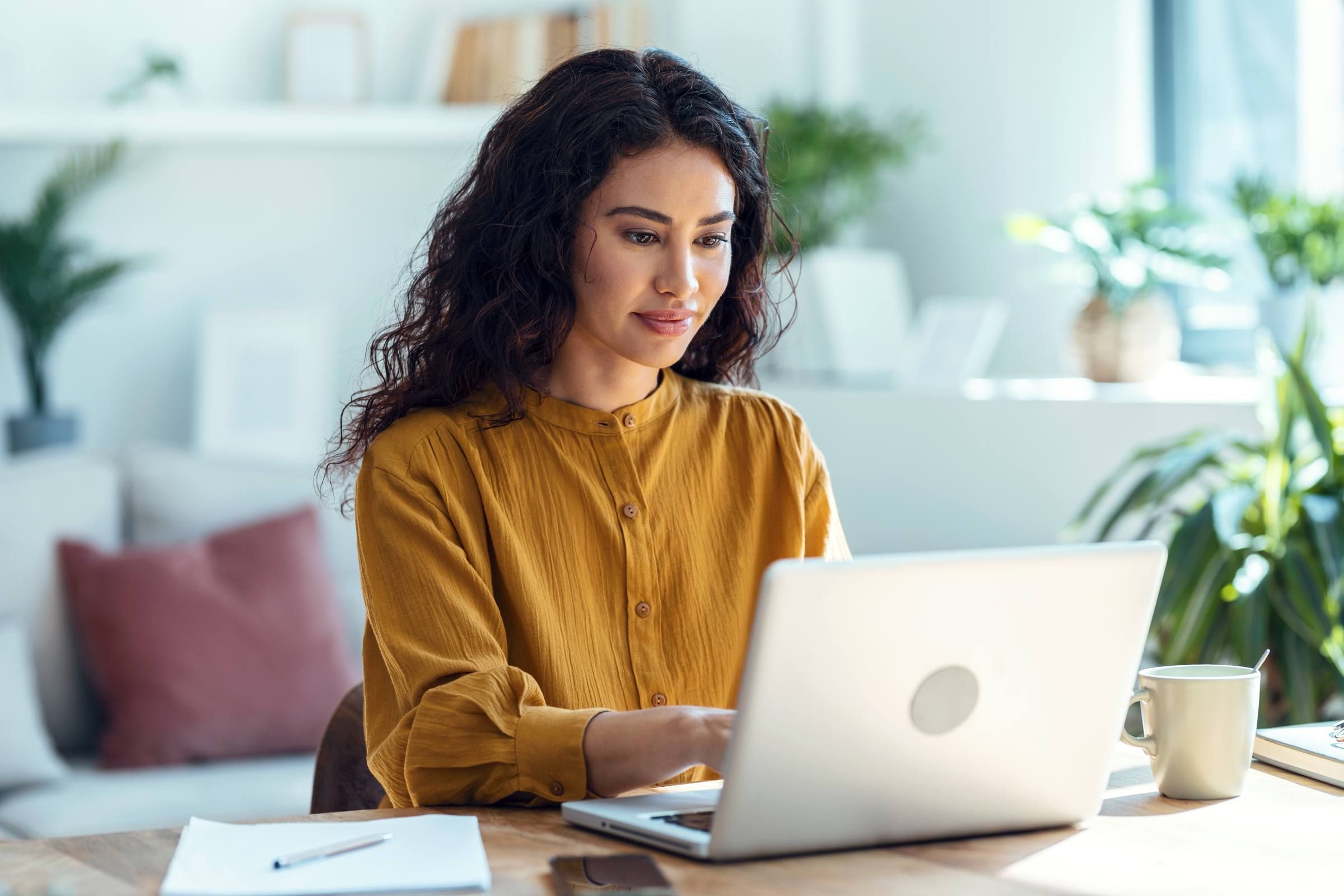 Concentrated business woman working on laptop in living room at home.