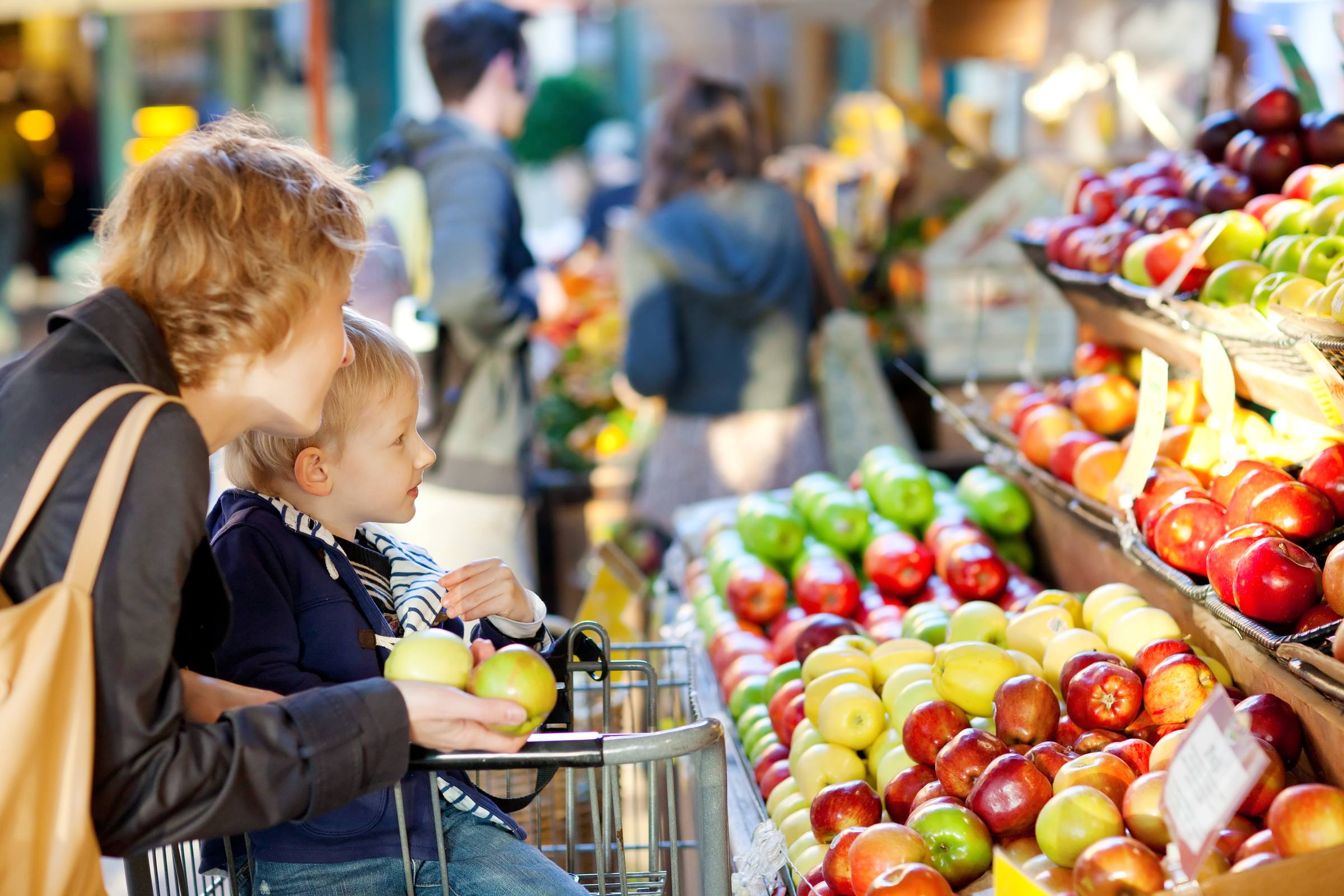 Mother and her toddler son buying fruits at a farmers market